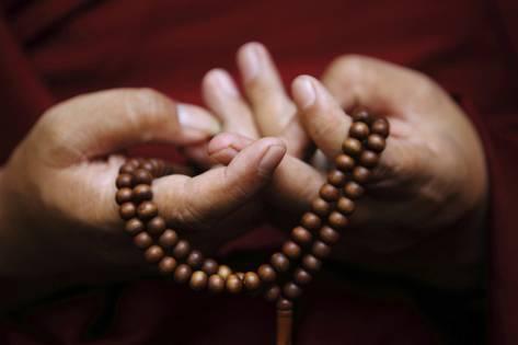 navesh-chitrakar-prayer-beads-are-seen-as-a-tibetan-monk-chants-prayers-during-tibetan-new-year-celebrations_a-G-13512330-14258384